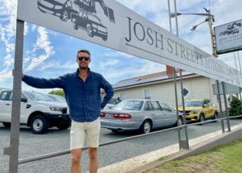Josh Streets from Josh Streets Automotive standing under a large outside the front of his caryard. Cars can be seen behind him.