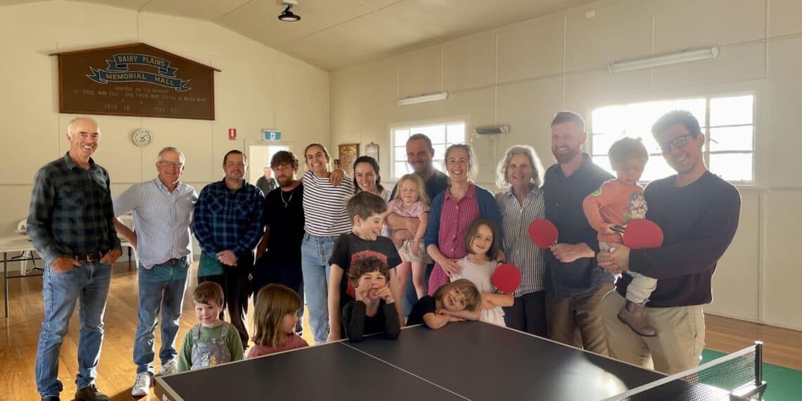 large group of people standing behind a table tennis table at Dairy Plains hall