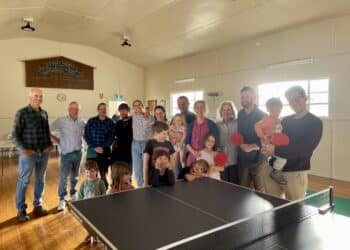 large group of people standing behind a table tennis table at Dairy Plains hall