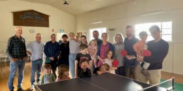 large group of people standing behind a table tennis table at Dairy Plains hall