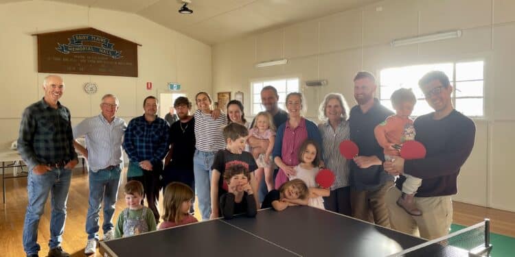 large group of people standing behind a table tennis table at Dairy Plains hall
