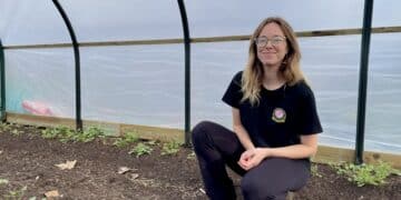 Chevi Robnik stands in her polytunnel, ranunculus growing in the beds beside her. Poetry in Petals